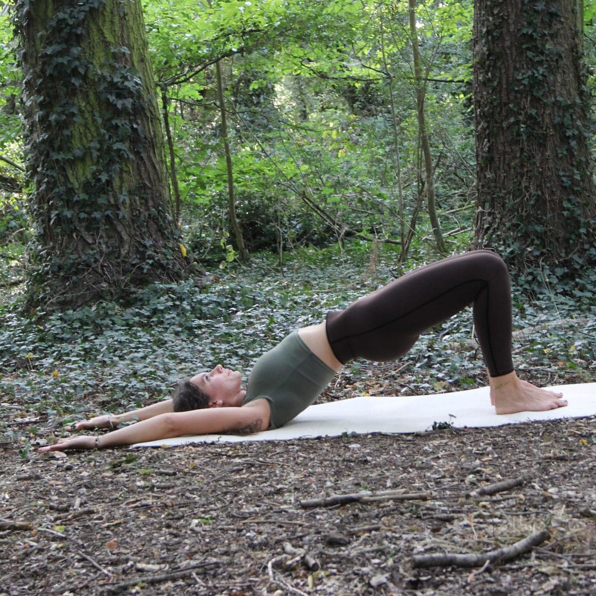A shoulder bridge held on a mat among the trees, the HabiMat idea of a workout